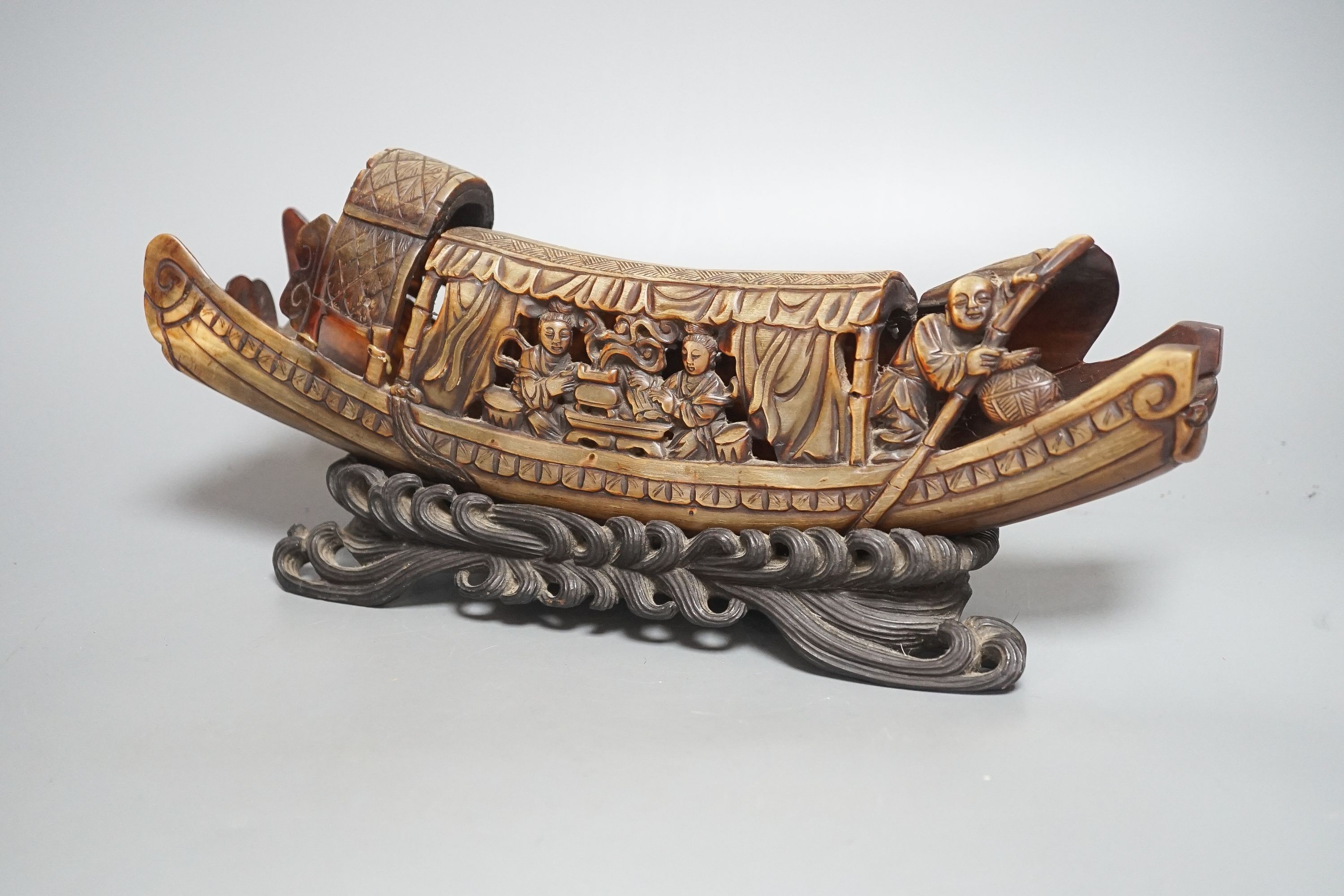 A Chinese horn carving of a junk boat, wood stand, 34cm